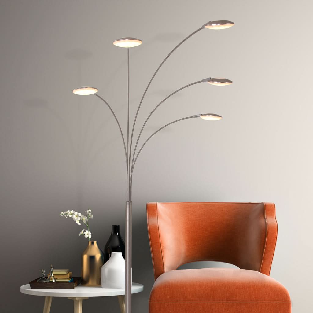 Lampe allumée près d'un fauteuil orange et d'une table d'appoint blanche