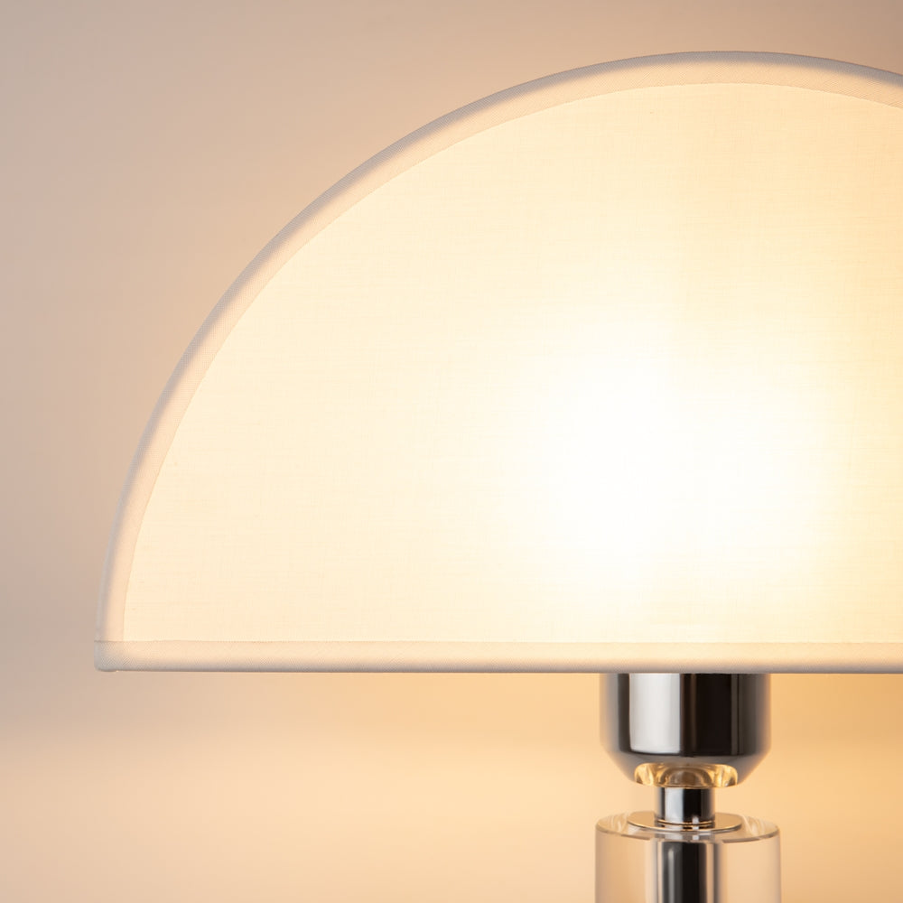 Gros plan de l'abat-jour allumé, lumière chaude diffusée par le verre opalin.