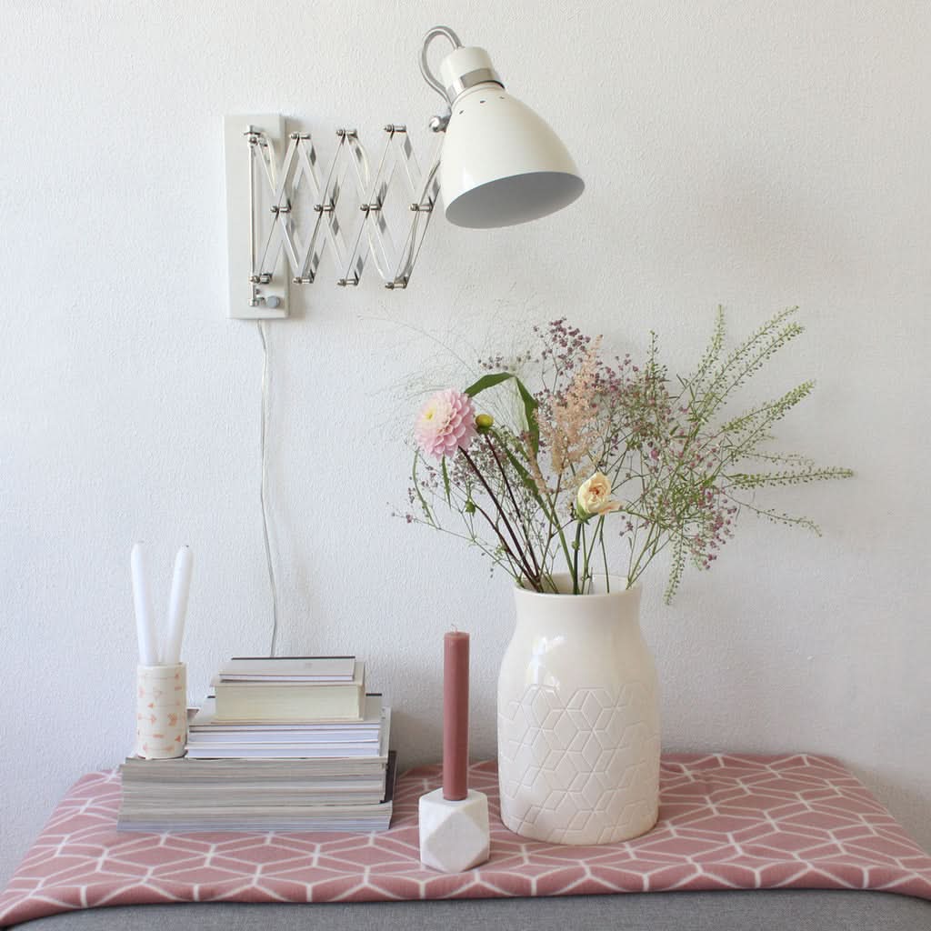 Applique fixée au mur au-dessus d'une table avec fleurs et bougie.