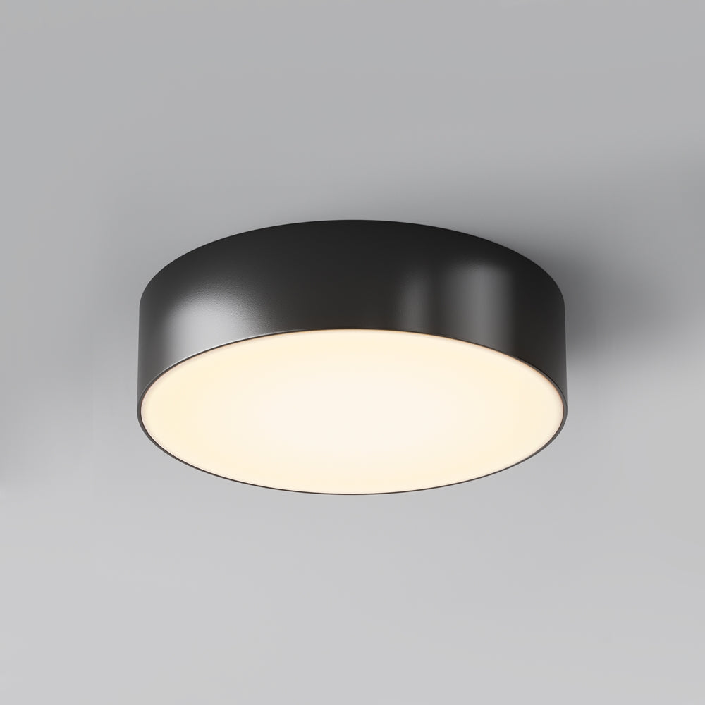 Luminaire noir rond vu de face sous un plafond, diffuseur blanc allumé