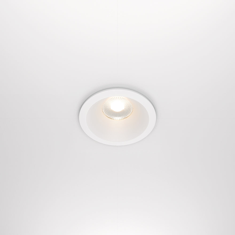 Spot encastré blanc vu de face, allumé dans un plafond blanc uni