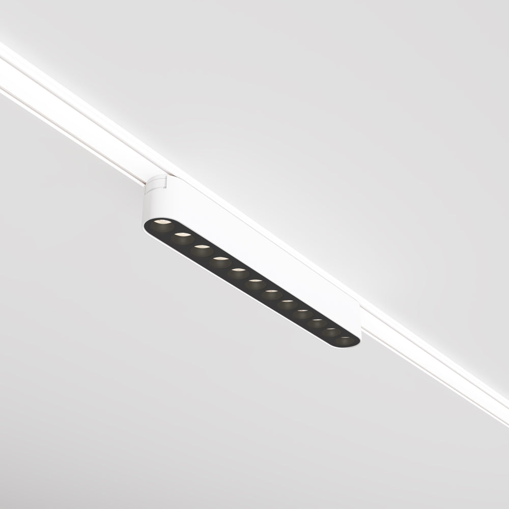 Projecteur linéaire blanc fixé sur rail, vu de trois quarts sous le plafond
