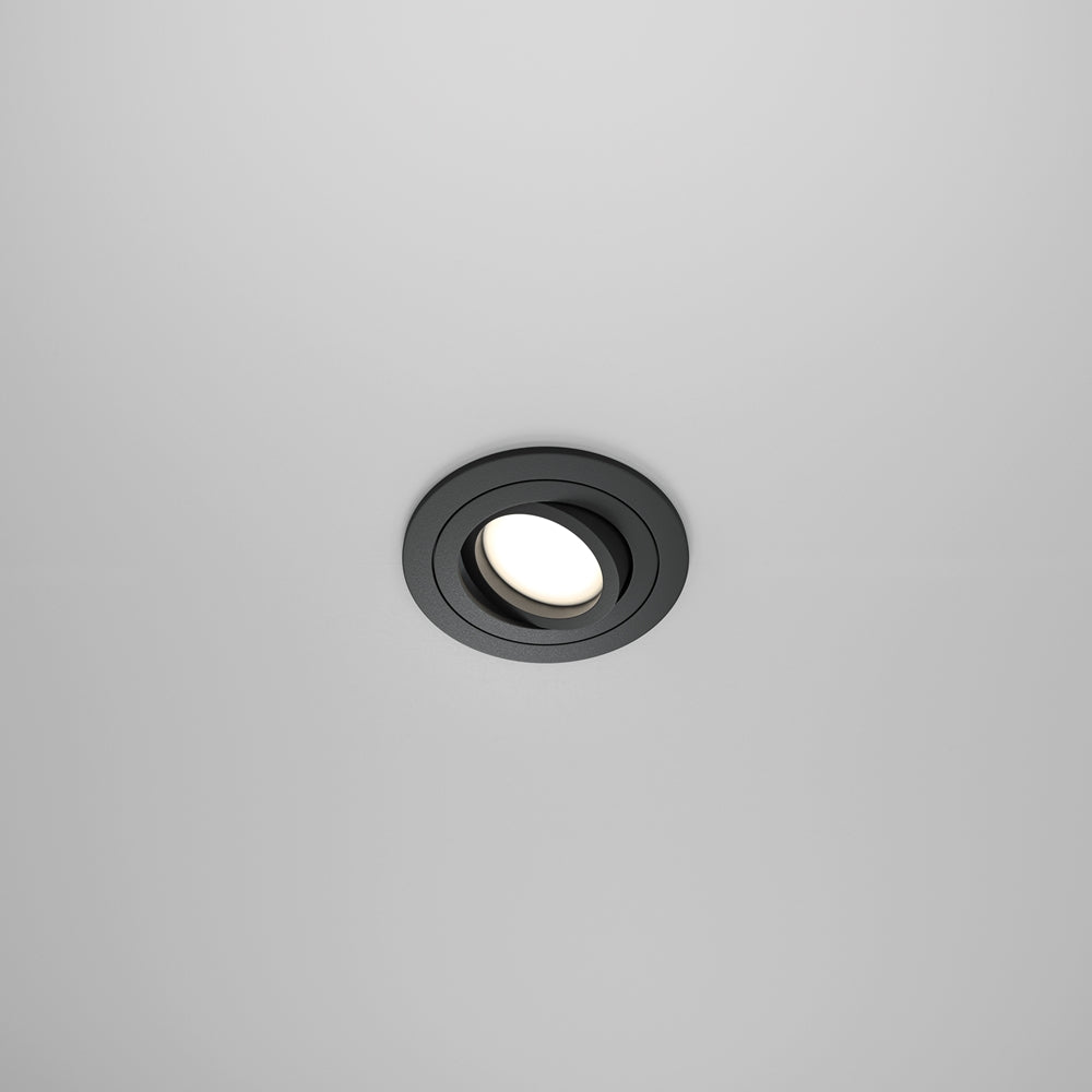 Spot encastré rond noir vu de face dans un plafond blanc