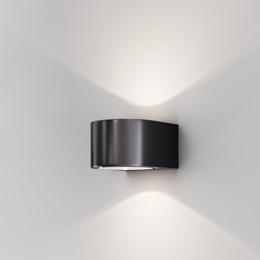 Applique murale noire demi-cylindrique fixée sur un mur blanc, éclairage haut et bas