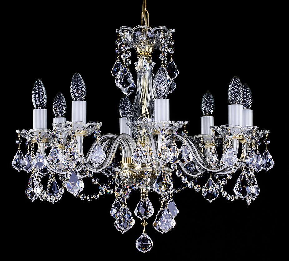 Lustre en cristal vu de face sur fond noir, bras dorés et pendeloques