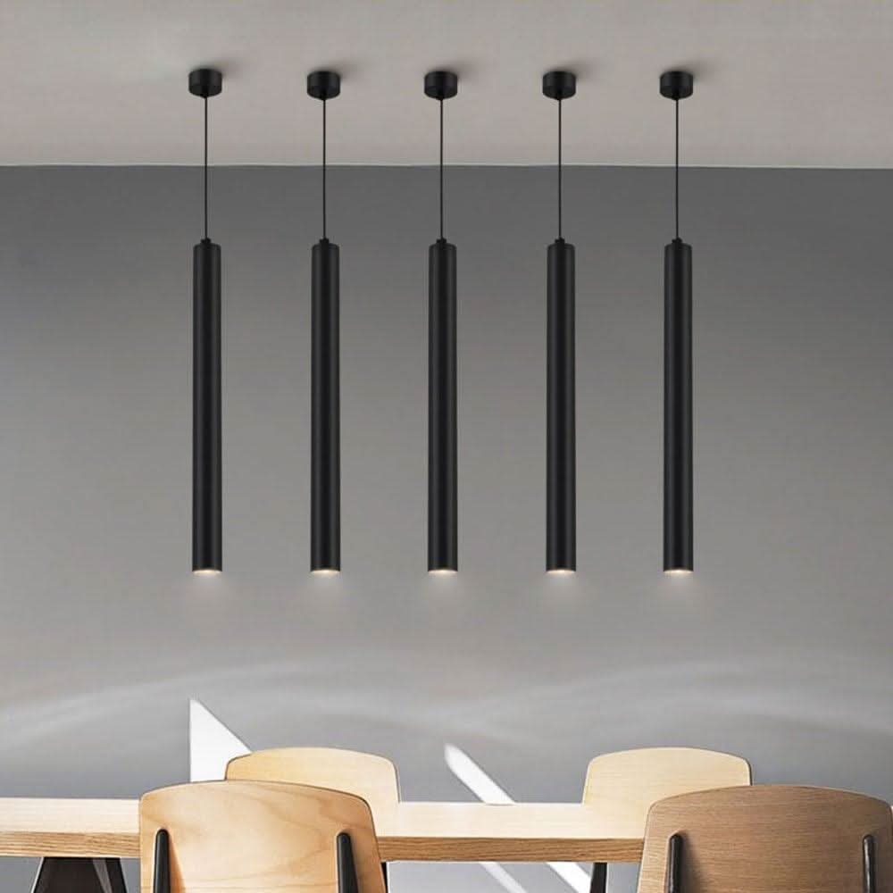Lampe suspendue noire à cinq cylindres alignés au-dessus d'une table en bois clair.