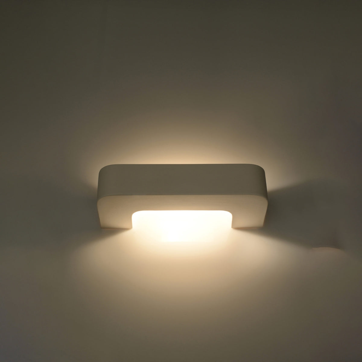 Mise en ambiance de l'applique allumée diffusant une lumière chaude sur le mur