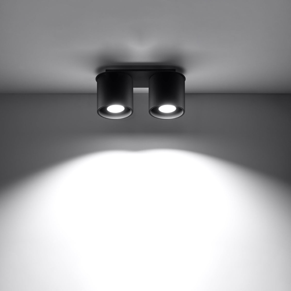 Plafonnier noir allumé fixé au plafond, éclairant une pièce sombre.