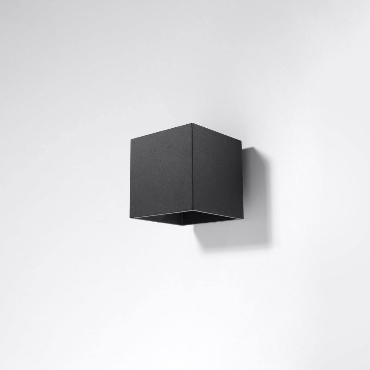 Vue du cube noir fixé sur un mur blanc avec ombre portée douce