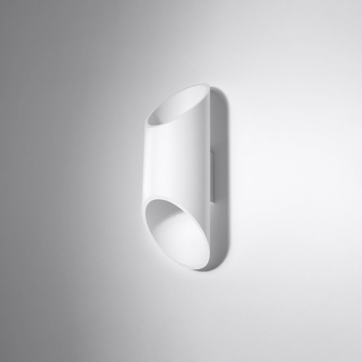 Applique cylindrique blanche fixée sur un mur gris clair, vue de biais