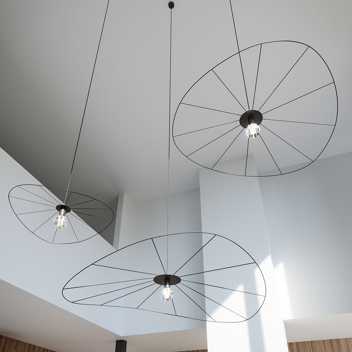 Vue rapprochée de trois lampes suspendues noires à structure filaire radiale