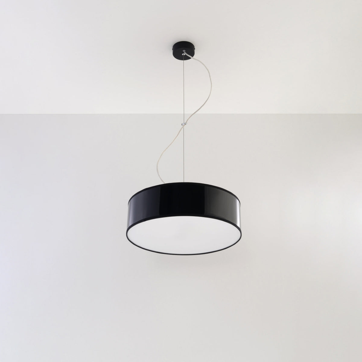 Suspension noire installée au plafond sur mur blanc, éclairage éteint