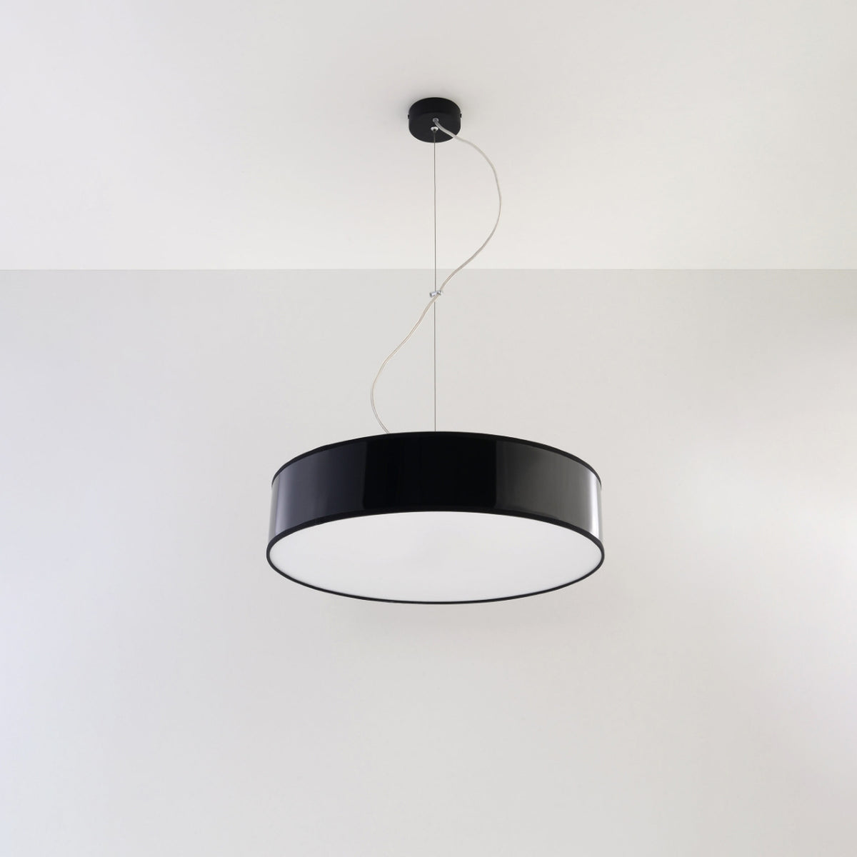 Luminaire suspendu fixé au plafond blanc, vue de trois quarts montrant la suspension.