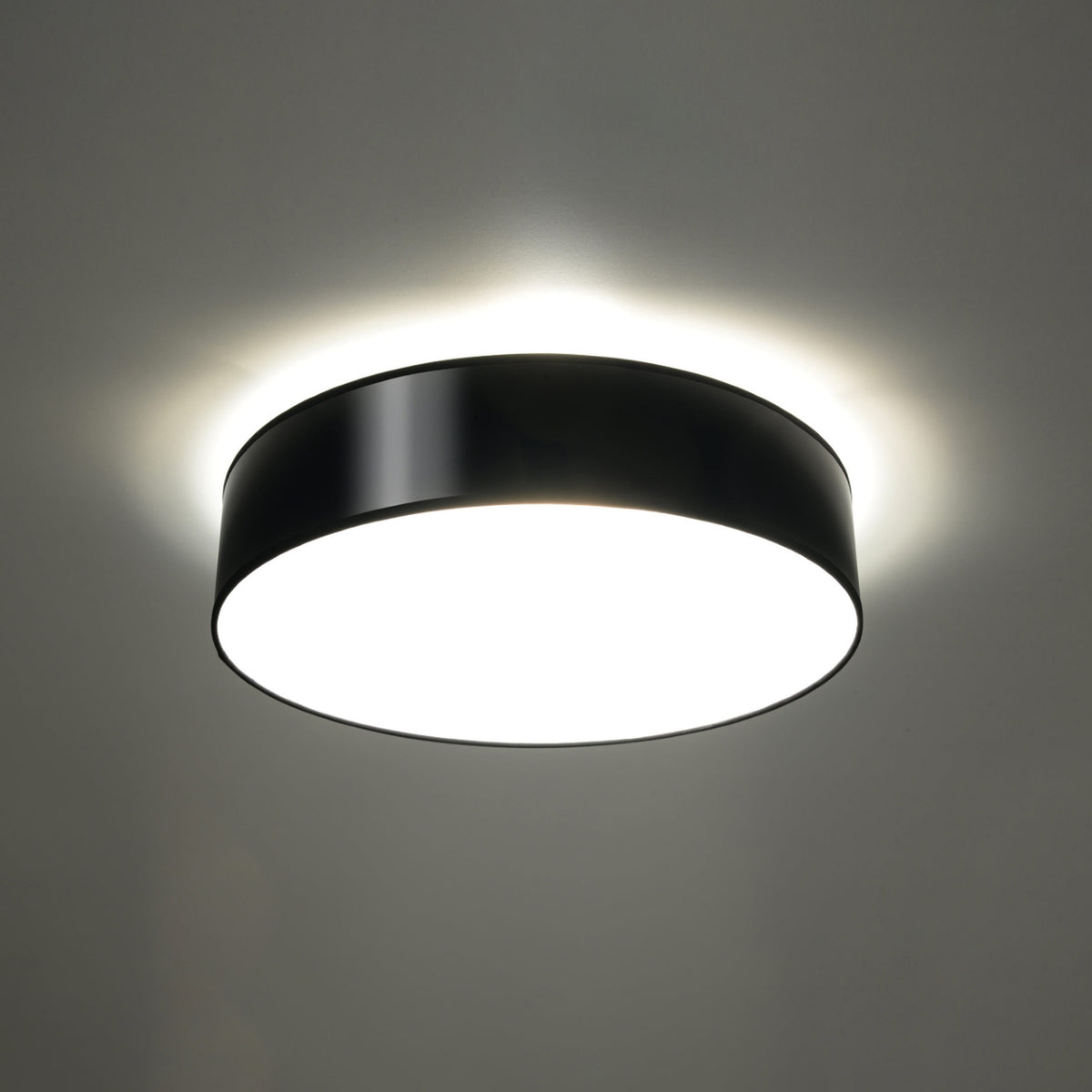 Plafonnier allumé diffusant un halo lumineux blanc sur la surface du plafond