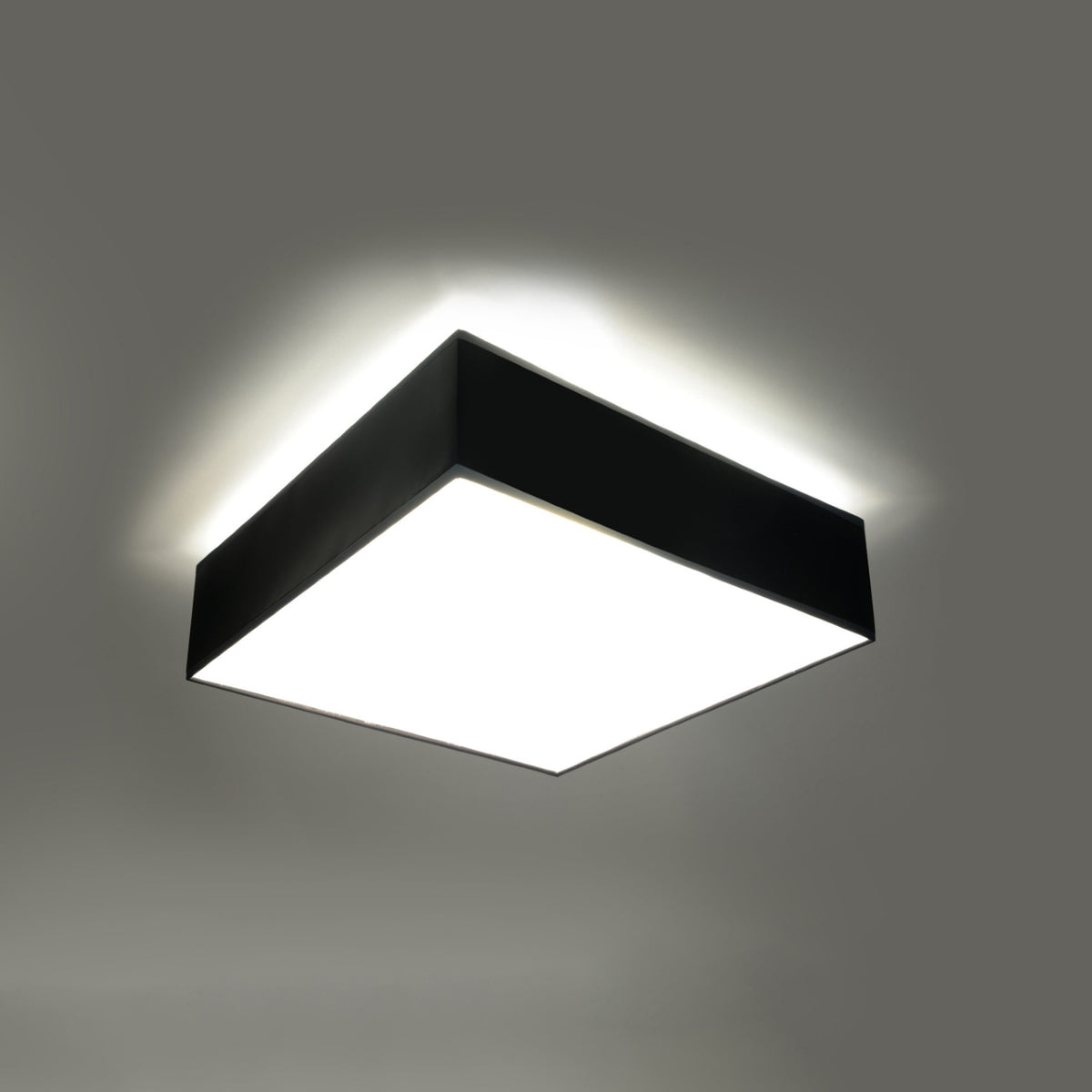 Plafonnier allumé au plafond avec halo lumineux diffus autour du cadre noir.