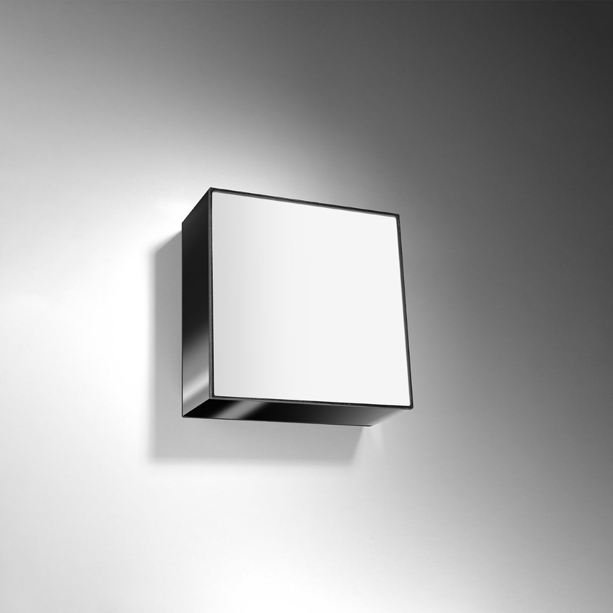 Luminaire carré monté au mur, allumé, projetant ombre et lumière sur la cloison.