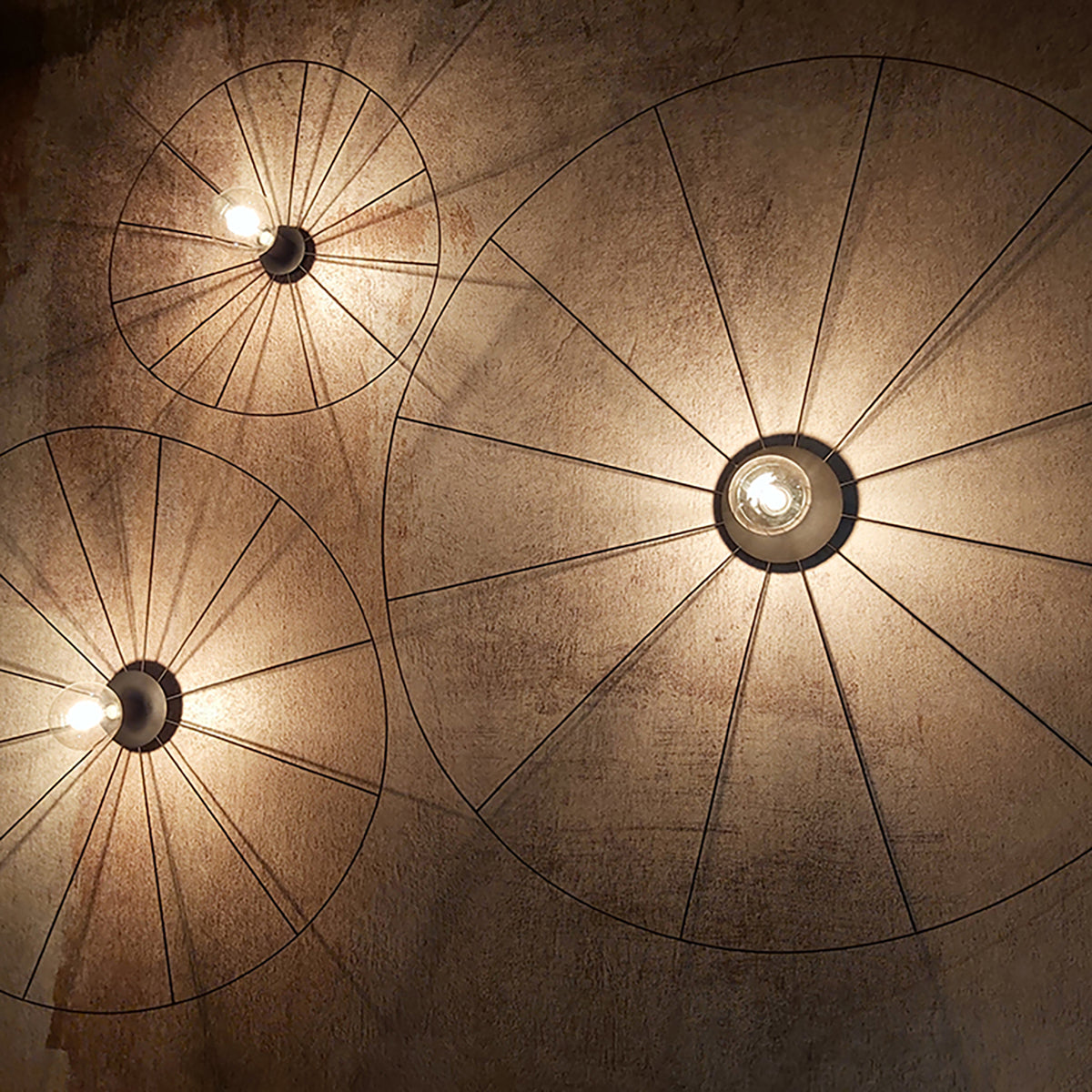 Mise en ambiance de trois luminaires fixés au plafond, éclairage chaleureux sur surface texturée