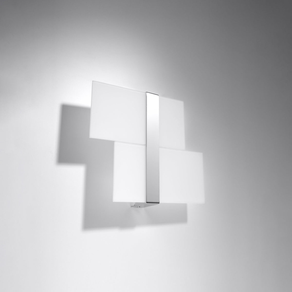 Applique murale allumée sur un mur gris, lumière blanche et ombre portée.