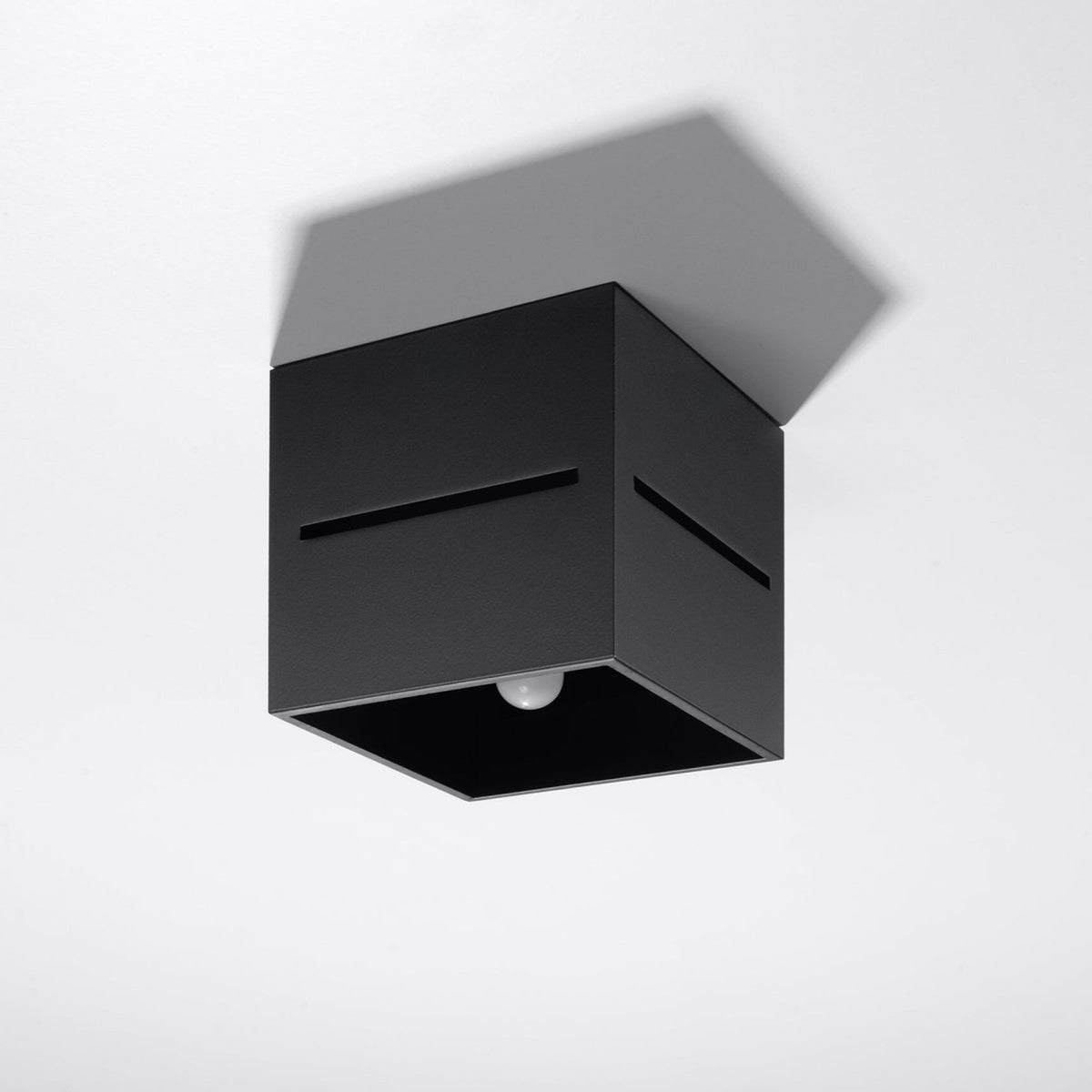 Plafonnier noir monté au plafond blanc, vu de dessous avec sa fixation et sa fente.