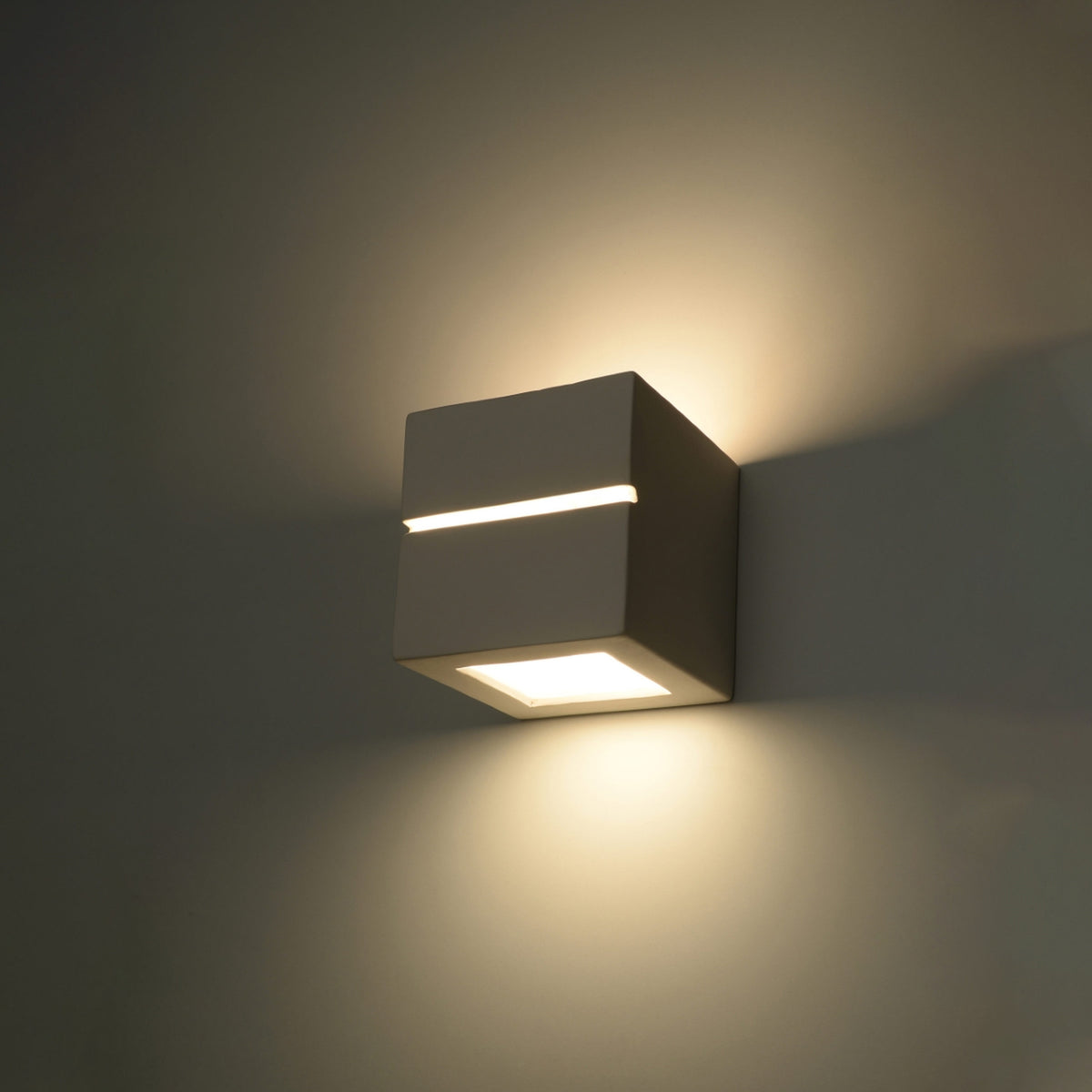 Mise en ambiance nocturne de l'applique allumée diffusant une lumière chaude.