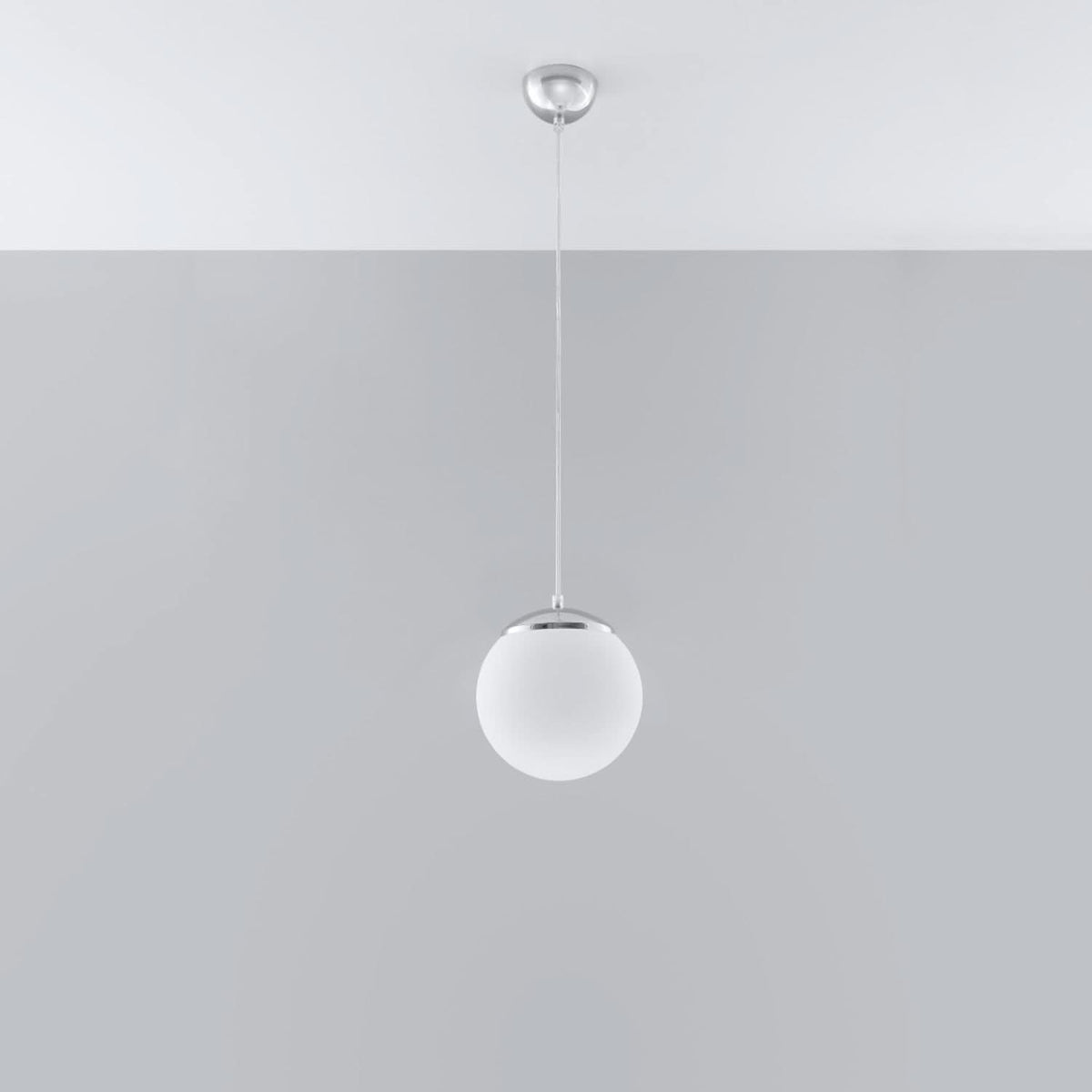 Lampe suspendue allumée, éclairant un mur gris dans une pièce sobre.