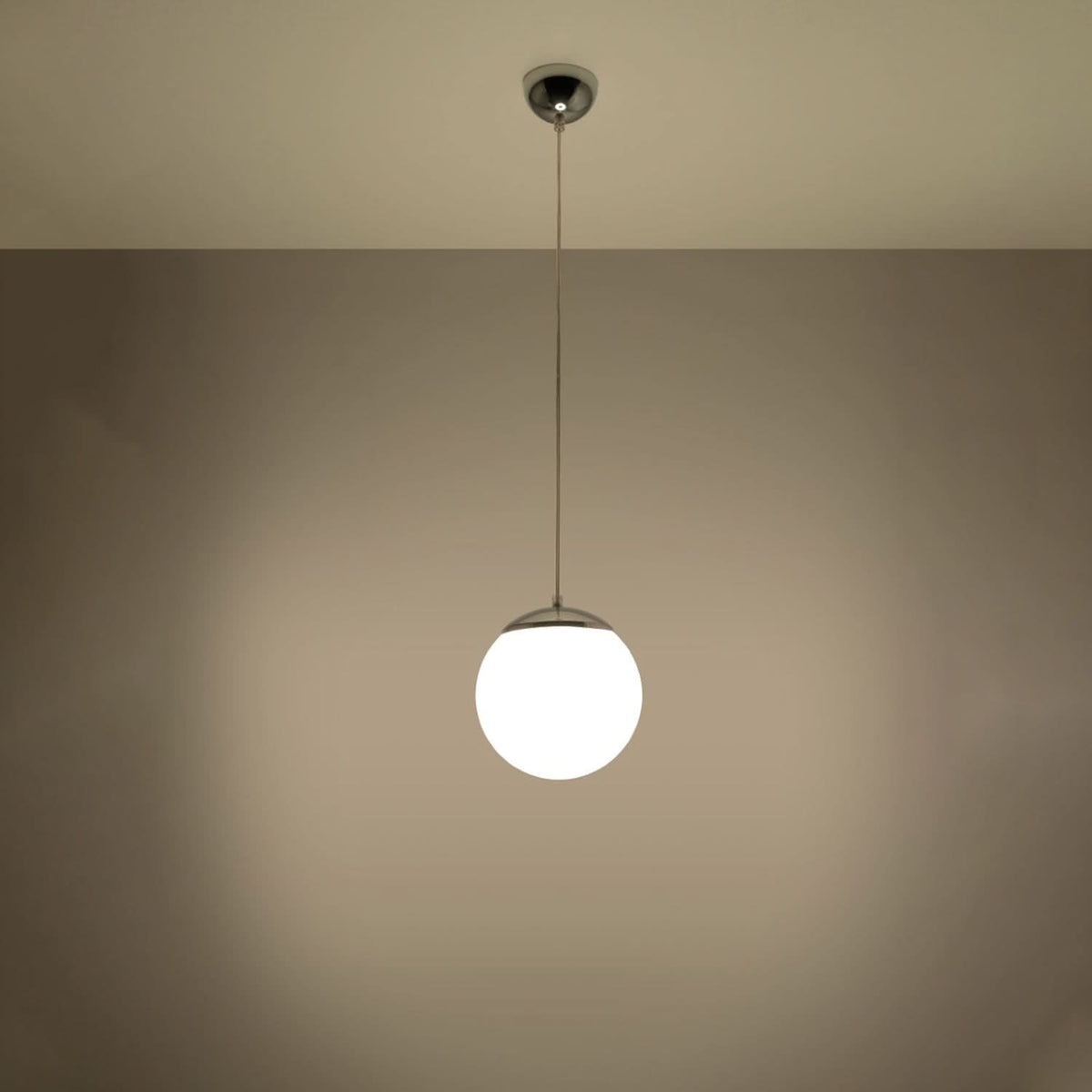Suspension boule éclairée, halo lumineux chaud sur fond beige en ambiance.