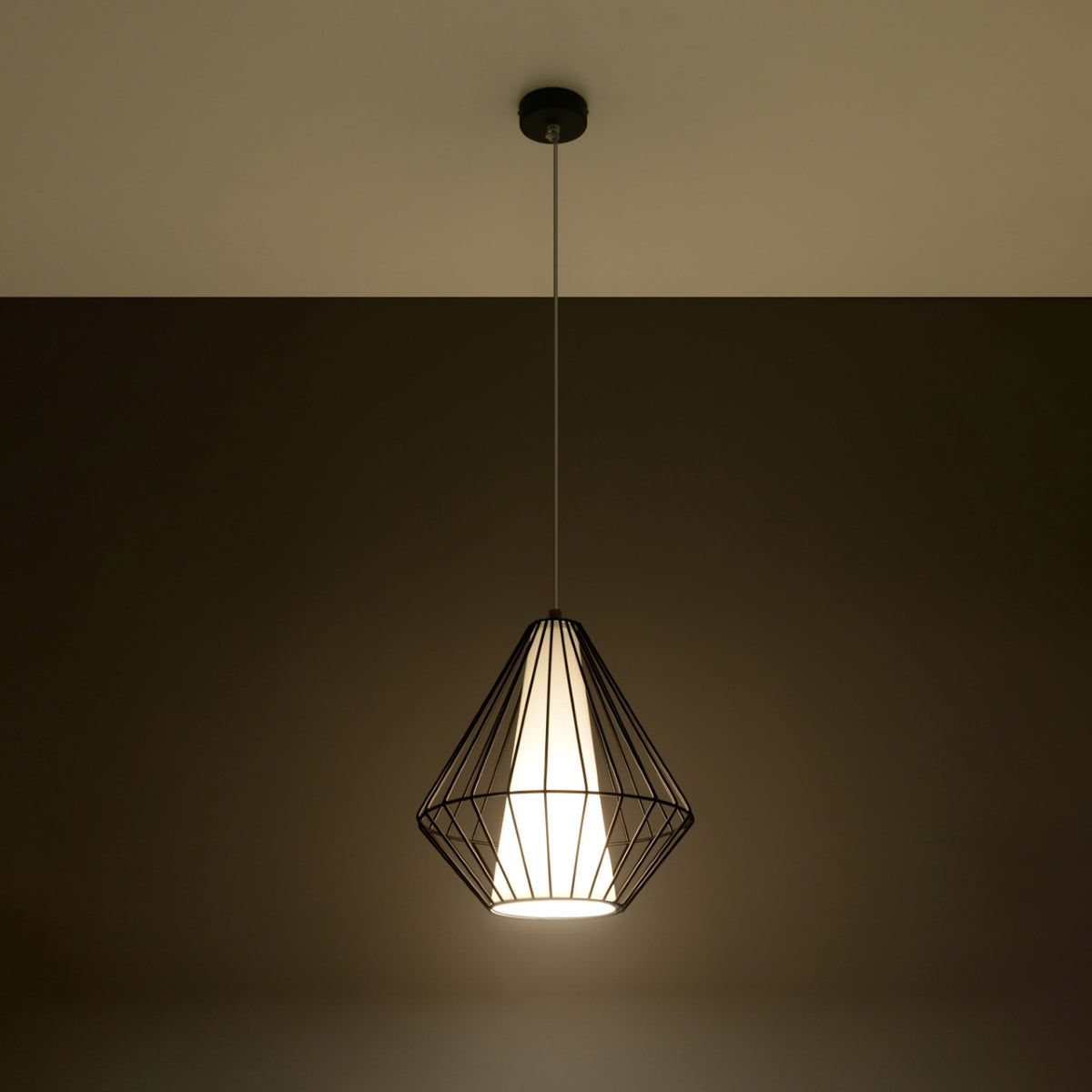 Suspension allumée dans une pièce sombre, lumière chaude diffusée par l'abat-jour textile.