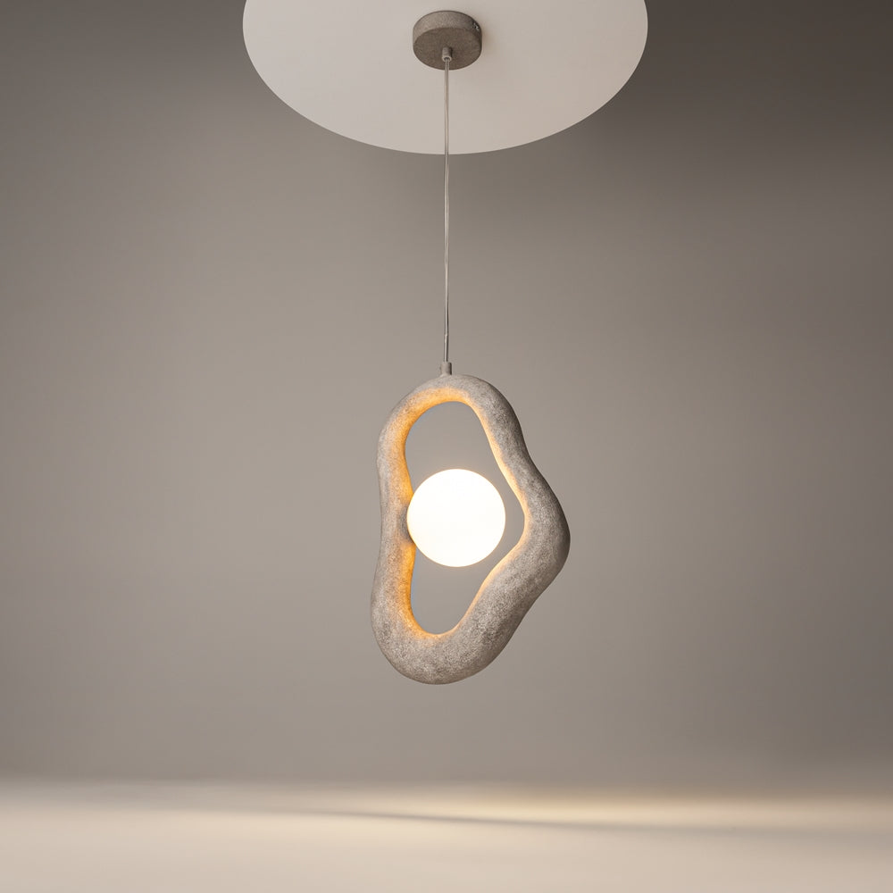 Luminaire allumé suspendu dans une pièce grise, halo doré diffus