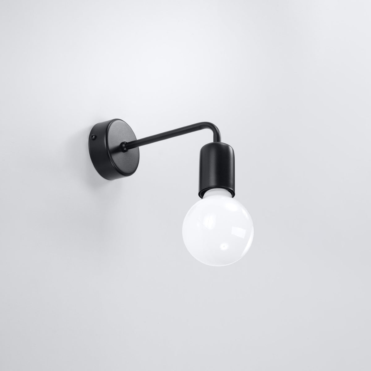 Applique murale noire fixée sur un mur blanc, ampoule globe éteinte.