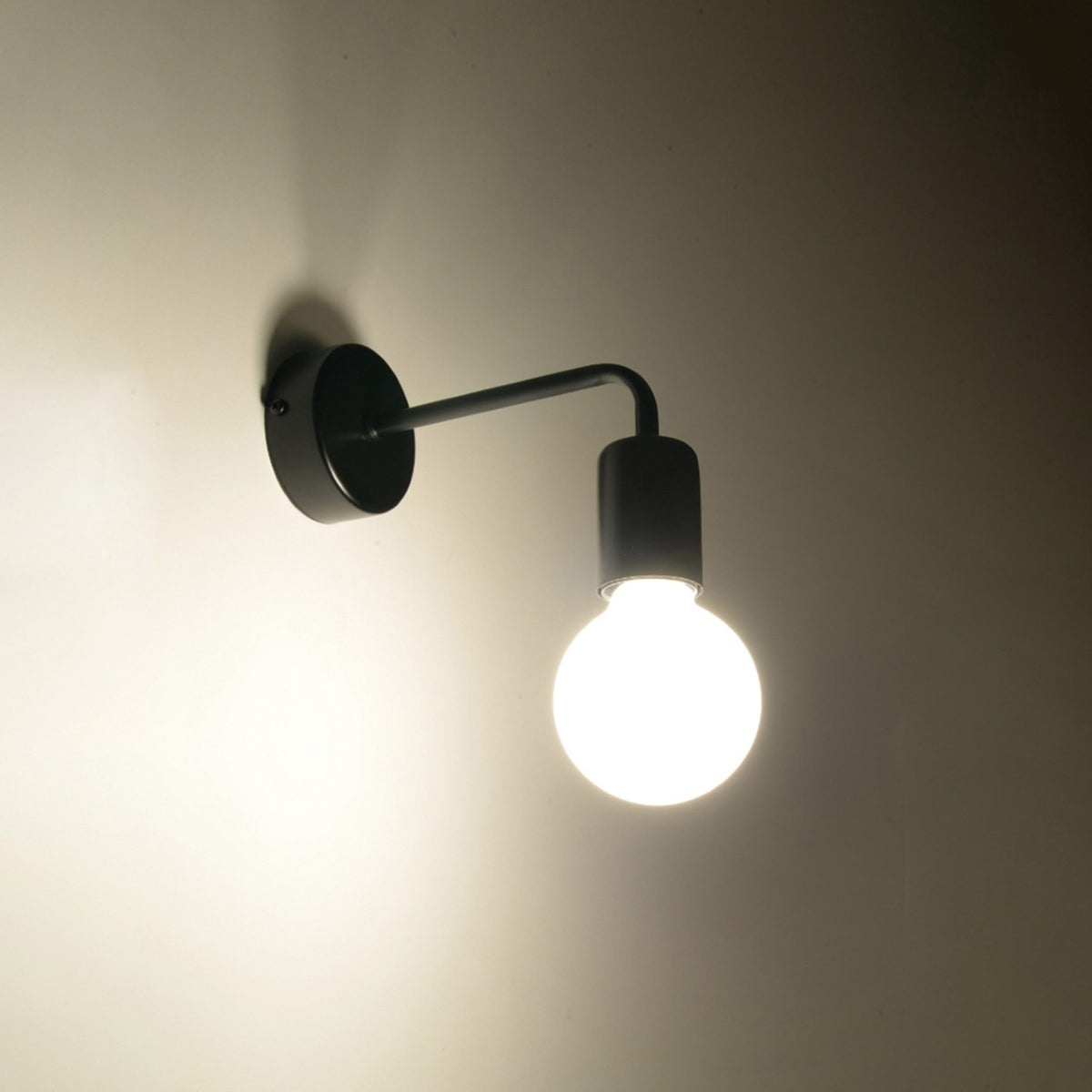 Applique murale allumée dans une pièce sombre, ampoule globe diffusant une lumière chaude.