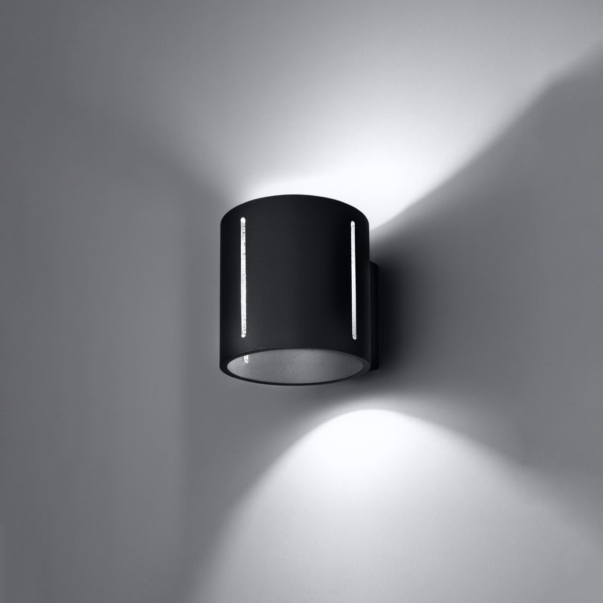 Vue rapprochée de l'applique murale noire en fonctionnement, fentes lumineuses et halos