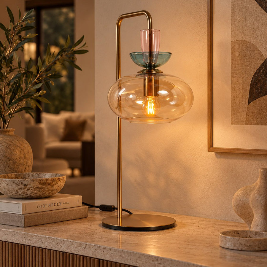 Lampe allumée posée sur un meuble, éclairant un salon chaleureux avec plante et cadre.