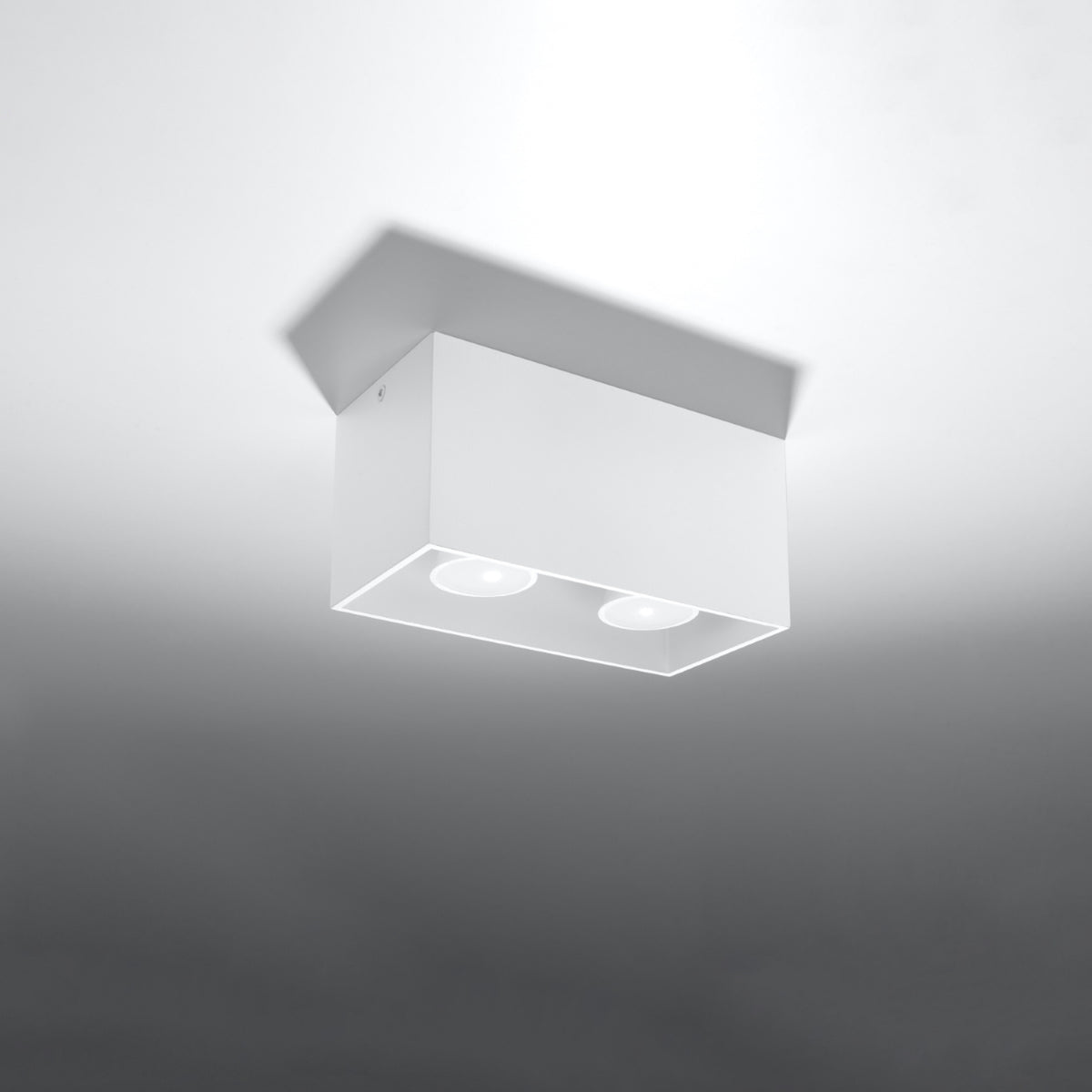 Plafonnier blanc allumé dans une ambiance sombre, lumière dirigée vers le bas.