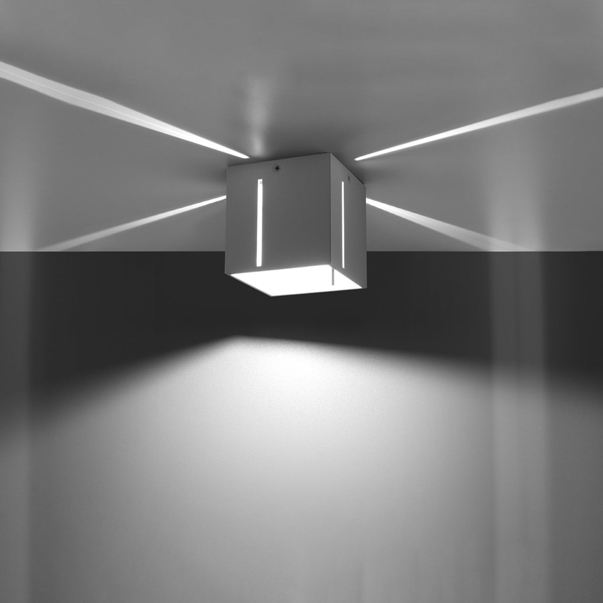 Mise en ambiance nocturne du cube lumineux allumé, éclairant un mur sombre.