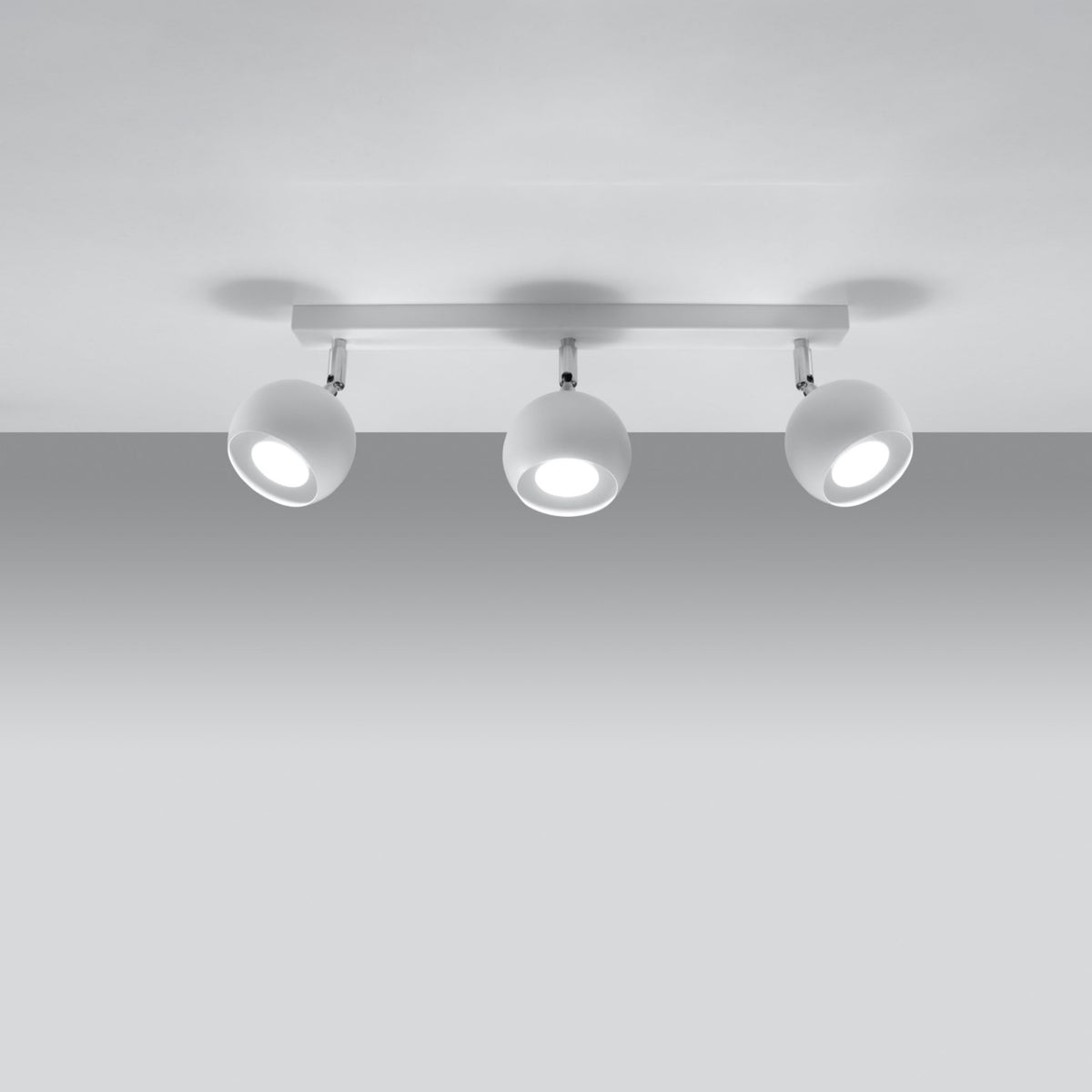 Trois spots allumés sous une platine fixée au plafond gris clair, ambiance