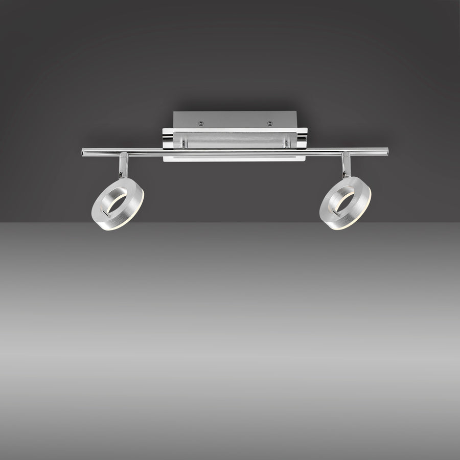 Vue de face sur fond gris dégradé montrant la finition chromée et les deux anneaux orientables.