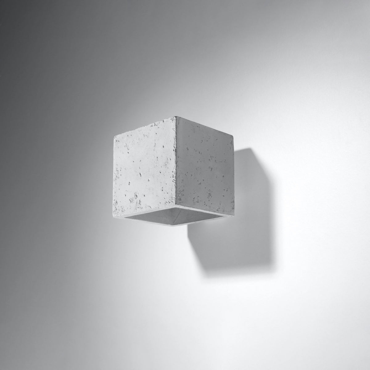 Applique murale cubique en béton gris clair, fixée au mur, avec ombre portée à droite.