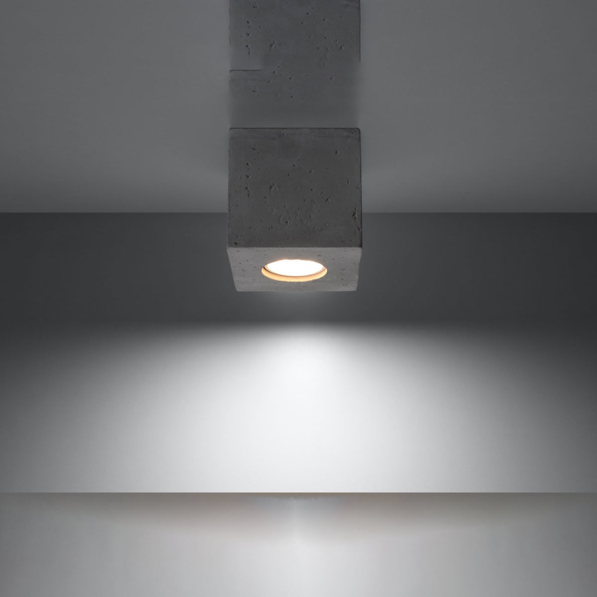 Luminaire allumé fixé au plafond projetant un halo lumineux vers le bas.