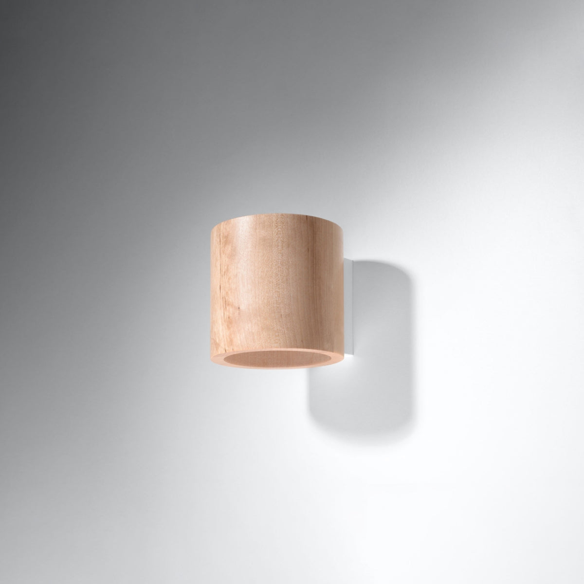 Petit luminaire mural en bois naturel sur fond gris uniforme, plan large.