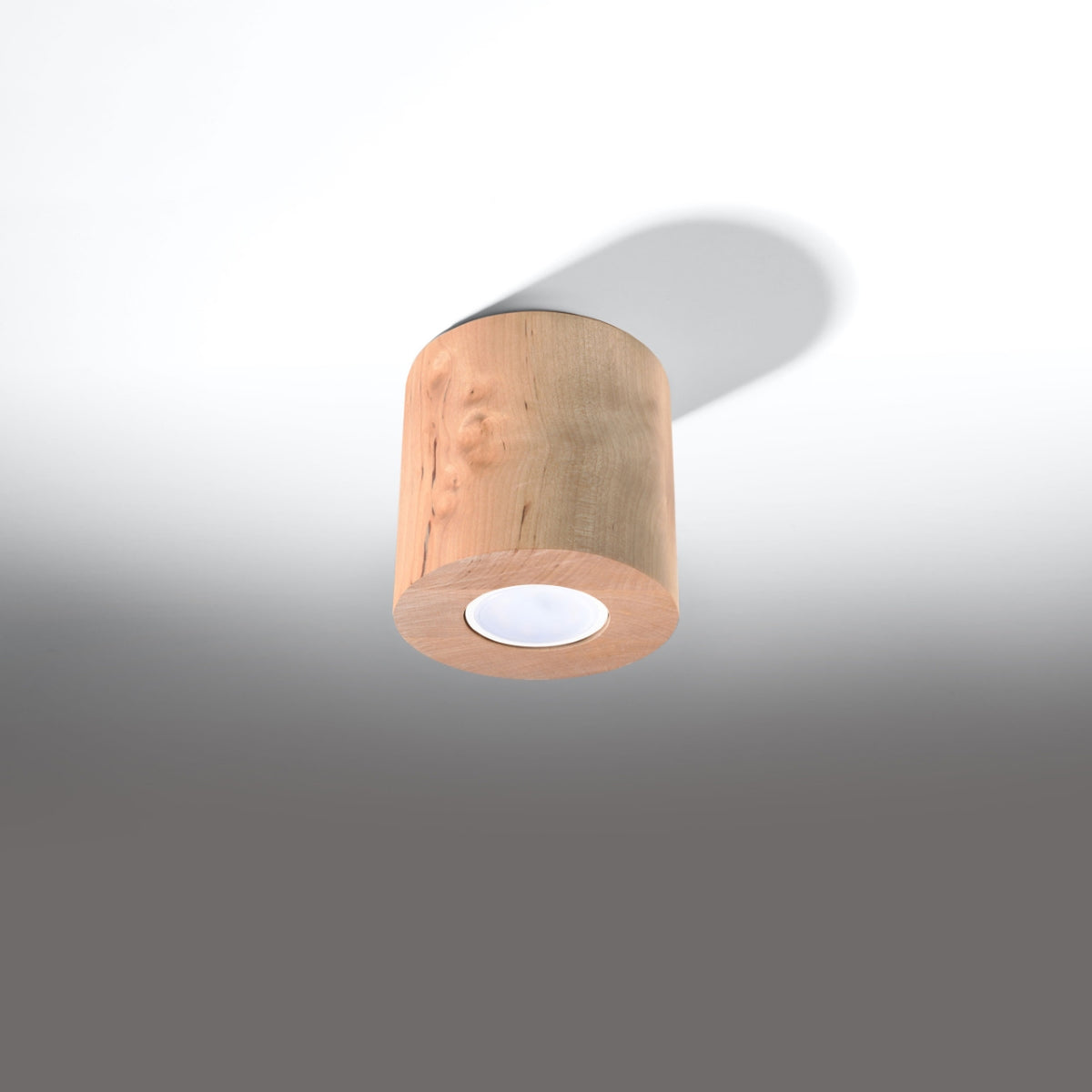 Spot cylindrique en bois suspendu au plafond blanc avec ombre portée nette