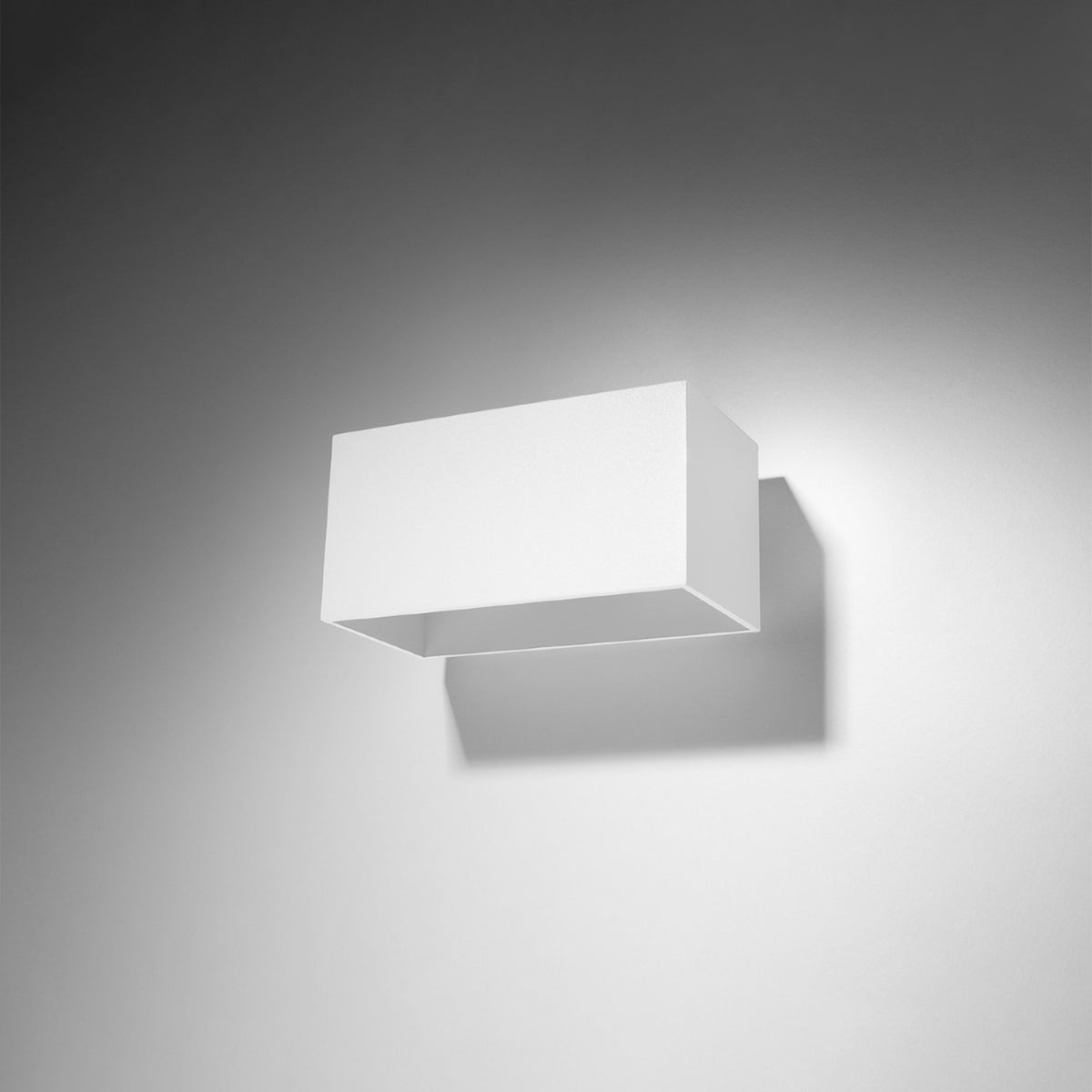 Applique blanche fixée au mur, éclairant la paroi avec un halo lumineux doux.