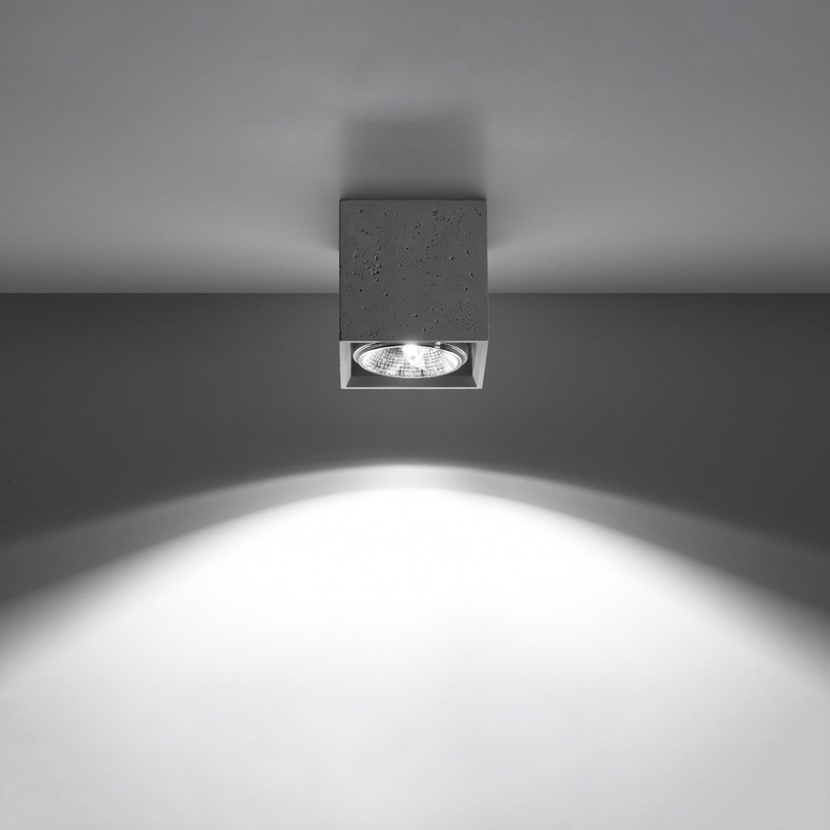 Spot allumé au plafond projetant un large faisceau lumineux blanc vers le bas