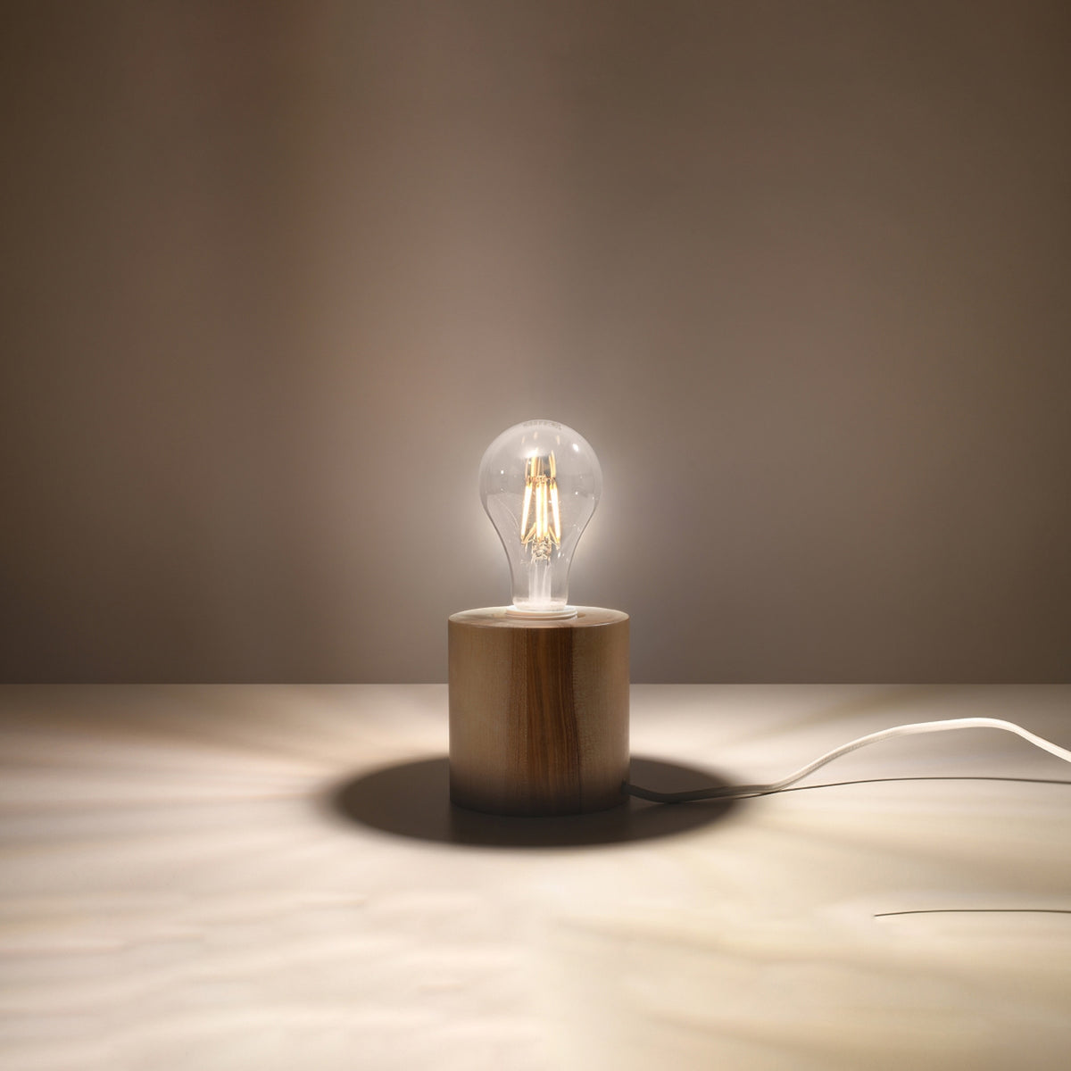 Lampe allumée diffusant une lumière chaude dans une pièce aux teintes beiges.