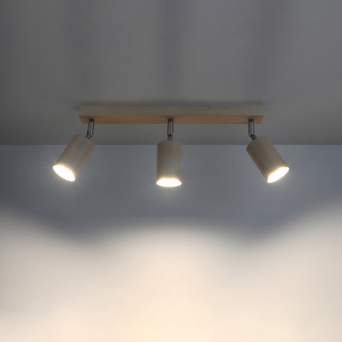 Mise en ambiance du plafonnier allumé projetant lumière chaude sur mur gris