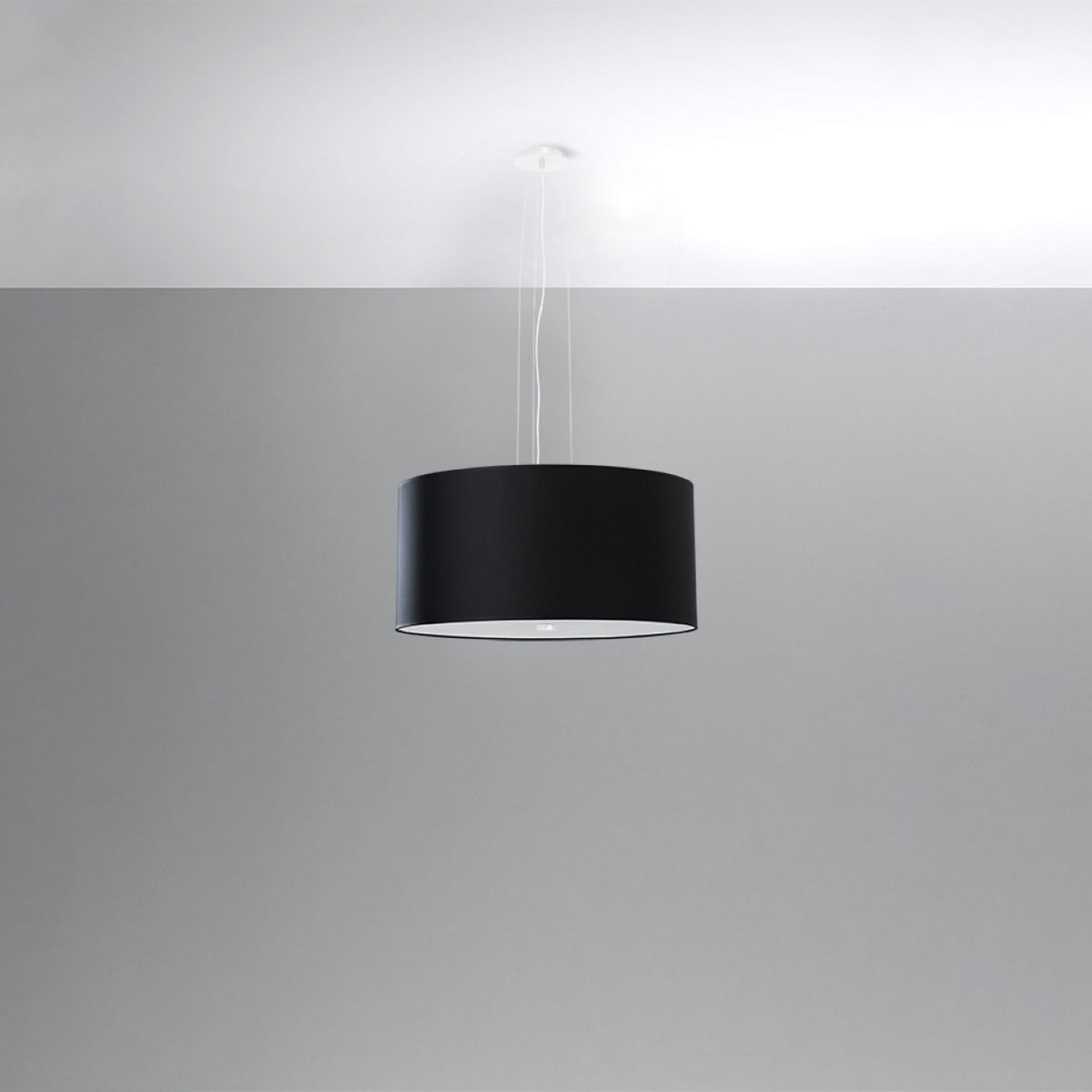 Vue du lustre noir dans un intérieur gris, abat-jour éclairé par le bas
