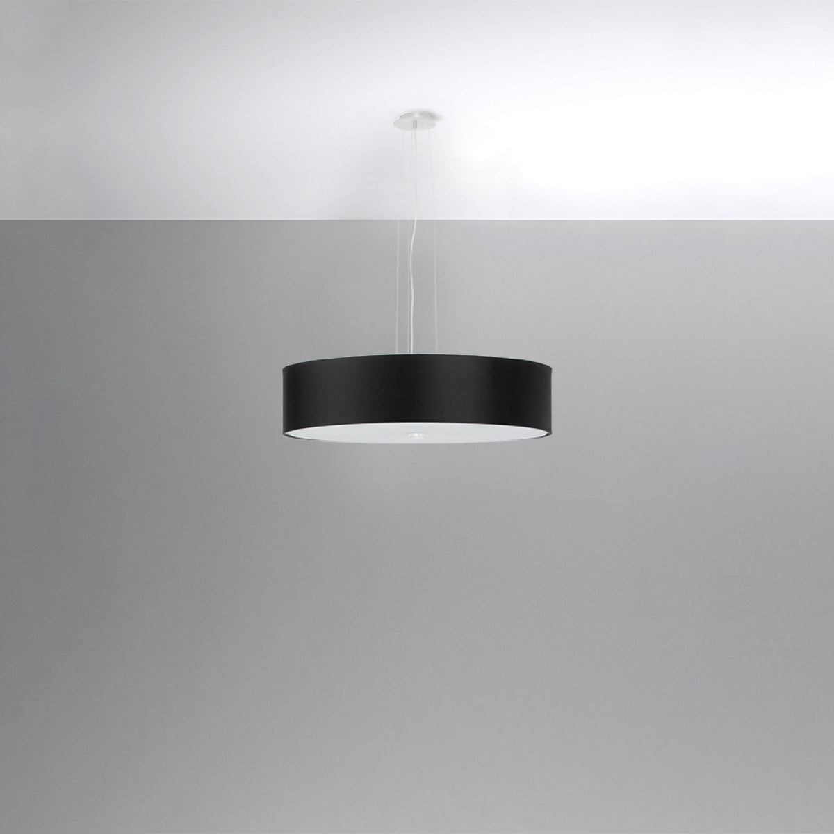Suspension noire vue de profil sur fond gris clair, câbles apparents et diffuseur blanc