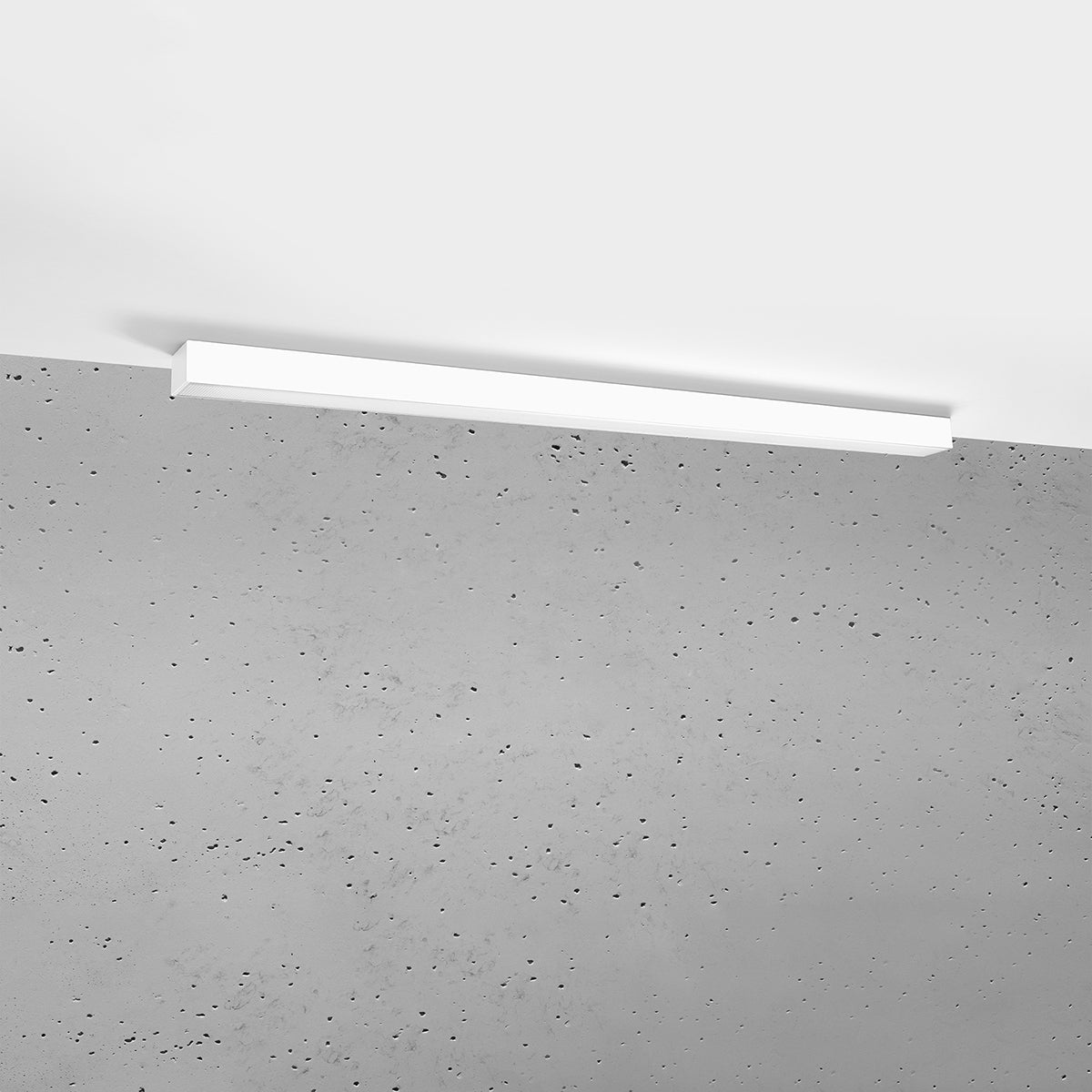 Plafonnier blanc fixé au plafond dans une pièce au mur béton brut