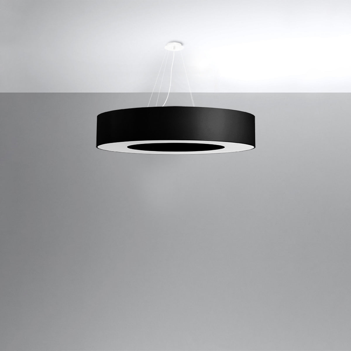 Vue du luminaire suspendu et de ses trois câbles fins sur fond gris
