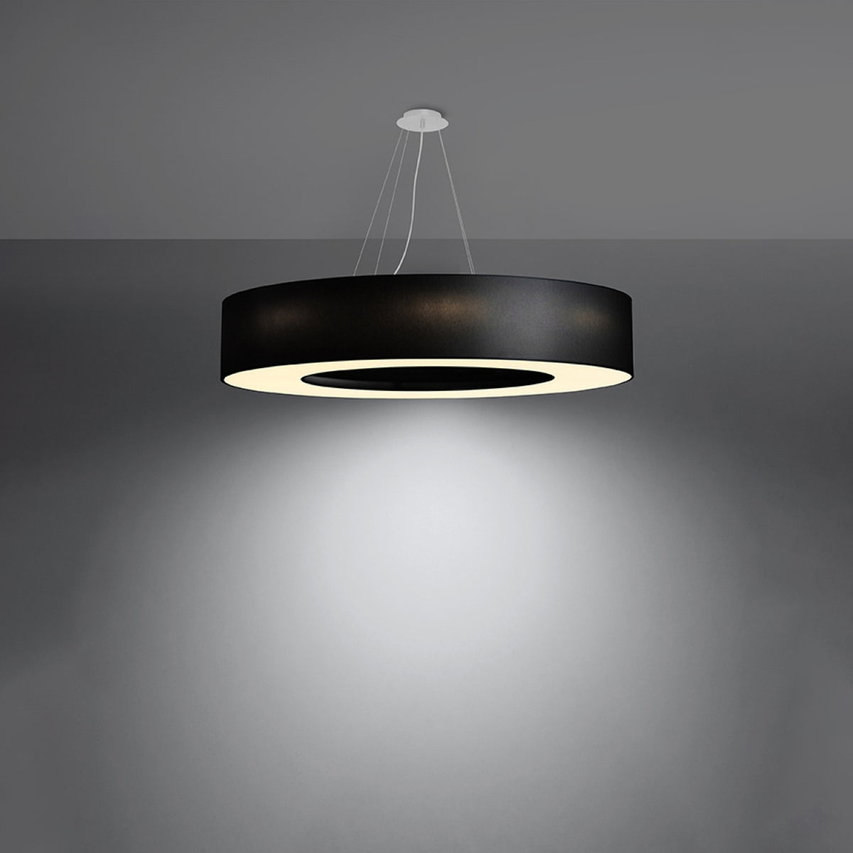 Luminaire allumé dans une pièce sombre, halo lumineux diffusé vers le bas