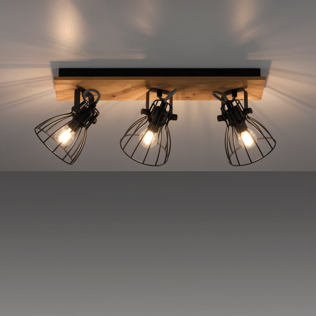 Luminaire installé au plafond, éclairé, projetant des ombres géométriques.